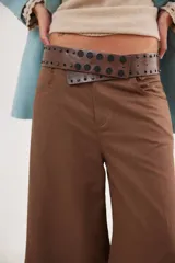 Faja de cuero vacuno color negro, con diseño ancho y decorada con remaches metálicos circulares en tonos oro y plata vieja, además de pequeños brillos incrustados.