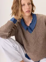 Buzo de lana color marrón topo, con cuello en V y diseño de punto calado en rombos en el frente y mangas.