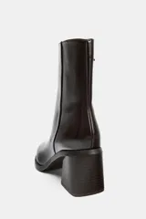 Botín de tacón alto en bloque, color marrón oscuro, con acabado brillante, punta fina y cierre mediante cremallera lateral.