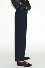 Pantalón tobillero de corte recto en color beige, con detalle de nervio delantero marcado. Incluye cinturón fino, bolsillos delanteros y cierre frontal con cremallera, botón interior y gancho.