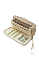 Billetera larga con cierre perimetral, confeccionada en material sintético con estampado botánico de flores silvestres sobre fondo claro. Cuenta con múltiples compartimentos internos para tarjetas, visor para documentos y un bolsillo interno con cierre. Incluye una correa de mano extraíble.