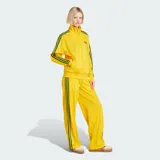 Pantalón deportivo Adidas de corte holgado, color amarillo brillante con las clásicas tres tiras verdes en los laterales y el logo del trifolio bordado en la pierna izquierda. Cuenta con cintura elástica y bolsillos laterales con cierre.