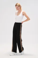 Pantalon de tejido de punto color crema, de corte ancho y tiro alto. Presenta una franja lateral con estampado animal print a lo largo de ambas piernas.