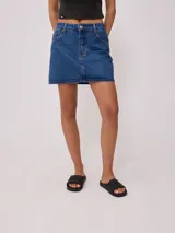 Falda corta de denim azul medio, con tiro alto y costuras contrastantes en color naranja. Presenta un corte recto y cierre frontal con botón metálico.