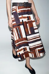 Falda midi de tiro alto en tejido de popelín con diseño evasé. Presenta un estampado geométrico en tonos tierra, crema y negro, e incluye un cinturón a juego con hebilla metálica dorada. Cuenta con cierre lateral mediante cremallera oculta.
