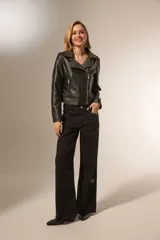 Chaqueta corta de cuero sintético negro con cuello solapa con tachas plateadas, cierre cruzado con cremallera, bolsillos con cremallera y corte holgado.