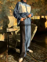 Pantalón de tiro alto con pierna ancha, confeccionado en denim azul y cuerina negra.