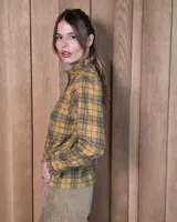 Camisa de algodón con estampado de rayas verticales finas, cuello alto con volados, cierre frontal con botones dobles y mangas largas con puños elásticos terminados en volados.