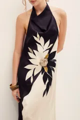 Vestido largo halter confeccionado en poliéster, con diseño bicolor en negro y beige, escote cruzado y detalle bordado de girasol en el frente.