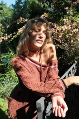 Vestido corto calado color terracota, con escote amplio y mangas largas. Incluye un accesorio tejido que puede usarse como collar o cinturón.