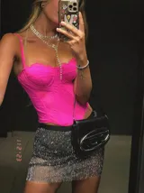 Corset o top estilo bustier color fucsia, con tirantes finos y detalles de encaje o tejido calado. Presenta un escote festoneado y un corte ajustado que termina en pico en la parte inferior.