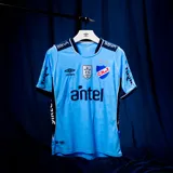 Camiseta de fútbol Umbro del Club Nacional de Football, edición especial en color celeste con detalles en azul marino. Incluye el escudo del club, el logo de Umbro y patrocinadores estampados.