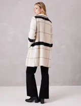 Chaqueta de tejido suave con estampado a cuadros en tonos beige y blanco, cuello con solapa y cierre de botón frontal. Incluye bolsillos delanteros.