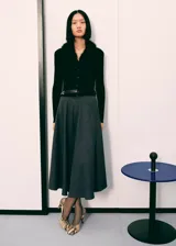 Falda midi de corte evasé en color gris oscuro, confeccionada en tejido mezcla de lana. Presenta tiro alto, cierre de cremallera lateral y bolsillos laterales.