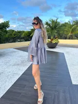 Vestido corto dorado con textura brillante, corte holgado, mangas largas con volados y cuello redondo.