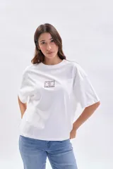 Remera blanca de manga corta con corte holgado y estampa central pequeña con diseño de flor y marco a cuadros.