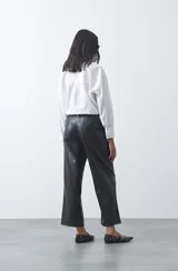 Pantalón de corte recto y pierna ancha confeccionado en cuero sintético negro, con acabado estructurado y tiro medio.