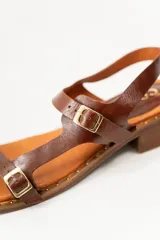 Sandalias negras de cuero con diseño de tiras rectas, hebillas metálicas y un mini taco de 1.5 cm. La suela tiene detalles de tachas pequeñas.