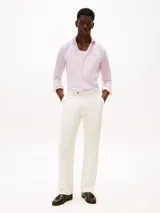 Camisa de hombre Tommy Hilfiger de manga larga a rayas verticales rosas y blancas, confeccionada en algodón regenerativo elástico. Tiene corte slim fit, cuello clásico, cierre con botones, puños abotonados y logo bordado en el pecho.