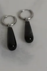 Aros tipo argolla de acero quirúrgico con dije colgante en forma de gota de piedra natural en tono marrón.