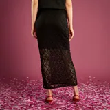 Falda larga de encaje negro con diseño de tubo y corte midi, confeccionada con una capa exterior de encaje floral y forro interior.
