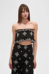 Top cropped negro, estilo strapless, con elástico en el busto y ruedo, y bordados blancos con motivos florales y geométricos.