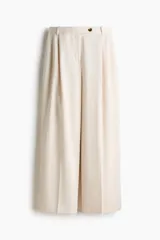 Pantalón sastrero color beige, de corte amplio y recto, con pinzas en la parte delantera y cierre frontal con botón.