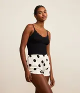 Conjunto de pijama short doll, con top de canalé negro con encaje en el escote y pantalón corto blanco con estampado de lunares negros y cintura elástica.