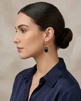 Caravanas colgantes de acero con baño de oro, compuestas por una argolla pequeña y un dije en forma de gota con piedra negra.