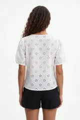 Blusa blanca de broderie con escote en V y cierre frontal de botones, mangas cortas abullonadas.