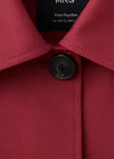 Chaqueta corta de algodón en color rojo, con cuello camisero, manga larga y cierre frontal de botones oscuros. Presenta dos bolsillos con solapa en el frente.