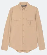 Camisa de manga larga color beige, con cuello camisero y dos bolsillos frontales con cierre en solapa.