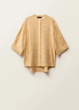 Camisa oversize de color beige con cuello de tira y cierre frontal de botones ocultos. Presenta mangas tres cuartos y un tejido con textura irregular.