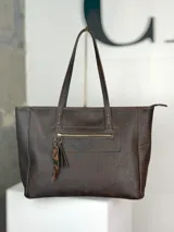 Bolso tipo shopper de cuero marrón chocolate, con doble asa de hombro, cierre superior y bolsillo frontal con cierre y tirador decorativo de cuero con estampa animal print.