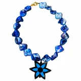 Collar corto de piedras de nácar azul con dije colgante en forma de flor de seis puntas, de color negro con centro y pétalos celestes.