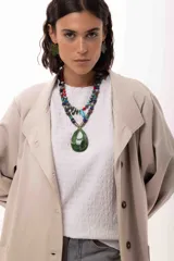 Collar corto de diseño artesanal compuesto por una variedad de cuentas de piedras naturales, cristales checos y acrílicos en tonos multicolor, incluyendo rojo, azul, turquesa y gris. Presenta un dije central en forma de gota color turquesa y cierre con cadena de acero quirúrgico ajustable.