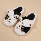 Pantuflas de diseño sin talón con forma de gato, confeccionadas en piel sintética suave. Presentan un patrón bicolor en blanco y negro con detalles bordados de ojos, nariz y bigotes, y cuentan con suela de goma antideslizante.