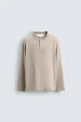 Jersey relaxed fit de punto en hilatura con mezcla de algodón y cashmere. Presenta cuello redondo con cierre frontal de botonadura y manga larga.