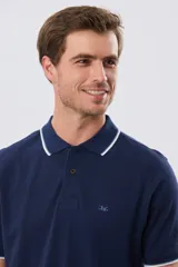 Remera polo de piqué azul marino, con cuello y puños de mangas cortas con ribete blanco en contraste, cierre frontal de dos botones y pequeño logo bordado en el pecho.