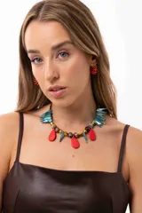 Collar corto con diseño artesanal compuesto por gotas de cristal checo, cuentas facetadas, piedras y colmillos de nácar teñidos en tonos turquesa y rojo. Incluye cadena de acero quirúrgico para regular el largo.