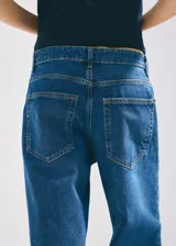 Jeans de tiro medio con diseño de pernera recta, estilo clásico de cinco bolsillos, presillas para cinturón y cierre frontal con botón y cremallera.