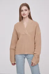 Sweater de tejido de punto en color beige, con cuello en V cruzado y mangas largas con puños ajustados.