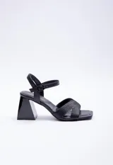 Sandalia alta de símil cuero negro con taco geométrico de 7.5 cm. Posee tiras cruzadas en el empeine con diseño pespuntado y tira ajustable con hebilla en el tobillo.