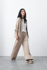 Pantalón de corte holgado y pierna ancha, con cintura elástica ajustable mediante cordón. Presenta bolsillos laterales y costuras verticales decorativas que recorren el frente de las piernas.