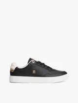 Zapatillas de corte bajo estilo tenis, confeccionadas en piel color negro. Presentan suela de goma blanca, detalle metalizado en el talón, ojal superior dorado y monograma TH metálico en el lateral.