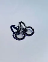 Aritos de acero quirúrgico con dije de resina transparente y strass violeta en forma de aro.