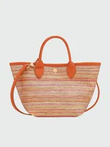 Bolso tipo cesta de tamaño XS, confeccionado en tejido de paja con detalles en cuero color naranja. Cuenta con asas cortas, correa larga ajustable y cierre de botón a presión con solapa de cuero grabada.