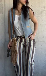 Chaleco de denim celeste sin mangas, con detalles de costuras decorativas en zig-zag y aplicaciones en tono suela en los bordes y bolsillos.