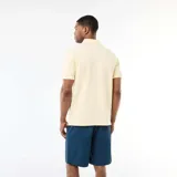 Remera tipo polo de color amarillo claro, con cuello clásico y detalles en blanco en el borde del cuello y las mangas. Presenta cierre frontal de botones y mangas cortas.