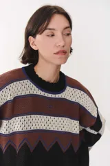 Buzo de tejido de punto con diseño geométrico y combinación de colores en contraste. Presenta cuello redondo, mangas largas y corte oversized.